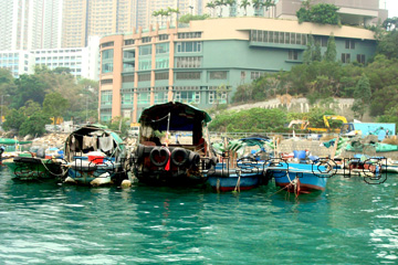 Hongkong und die Farbe vom Meerwasser mit ein paar Booten sowie einem Hotel mit Dachterrasse das sieht man auf dem Bild.
