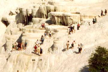 Bizarr aussehende weiße Kalkterrassen von Pamukkale und Touristen die barfuß auf den Terrassen laufen, in Kleinasien, Türkei.